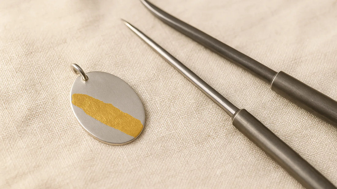 Keum-boo gold foil bonded to a silver pendant, with burnishers on cream linen