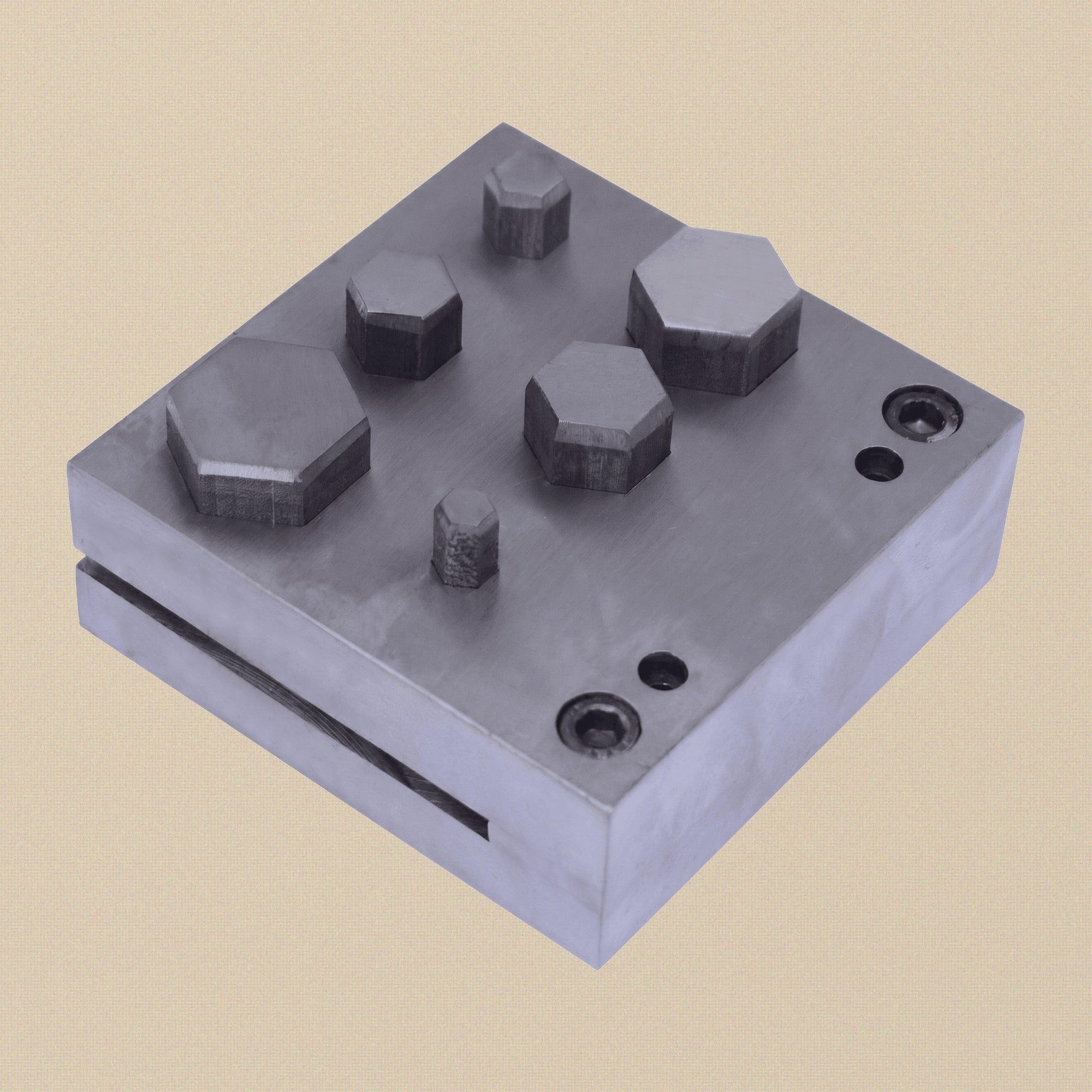 Close-up of the six hexagon-shaped apertures in the hardened steel die block.