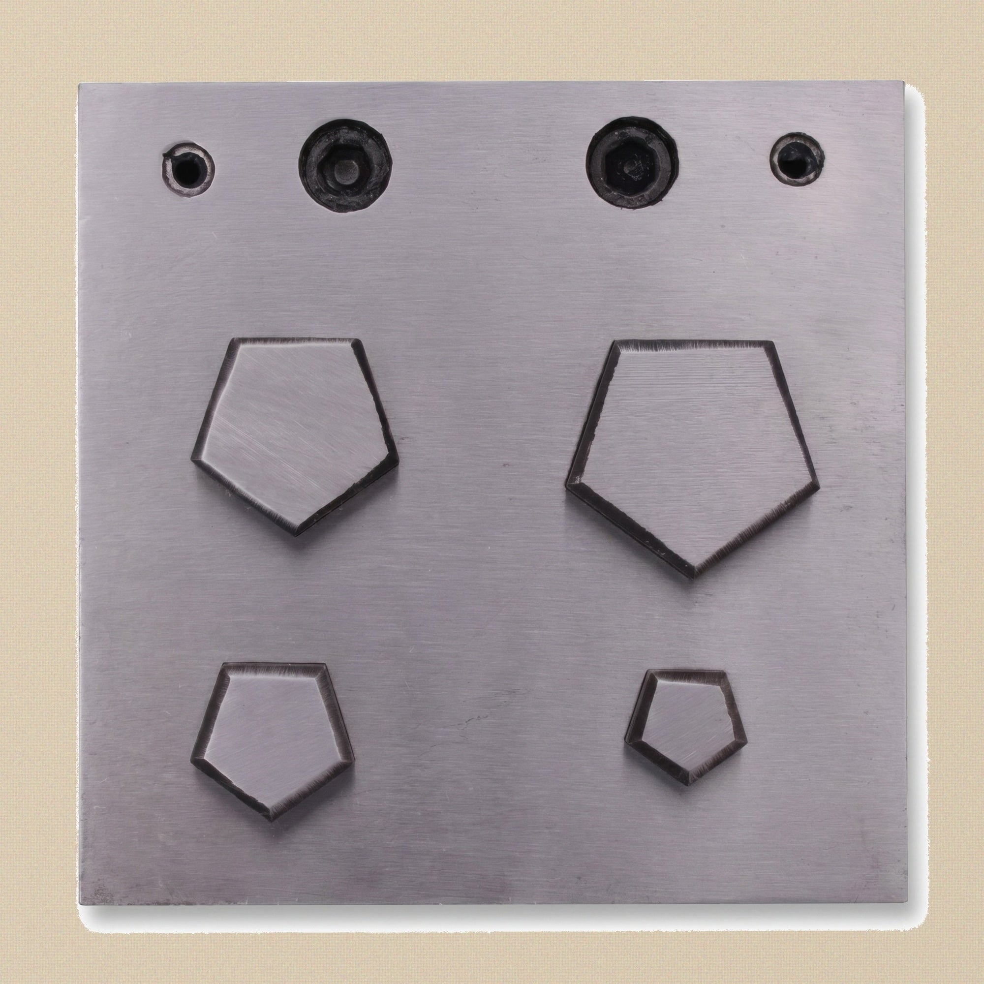 Top-down view of the steel die block showing the four pentagon-shaped cutting slots.