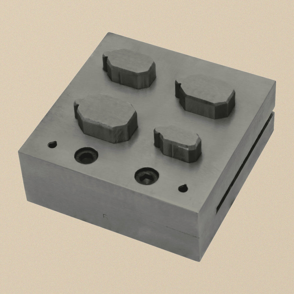 Close-up of the emerald-cut die slots on the 76mm square steel disc cutter block.