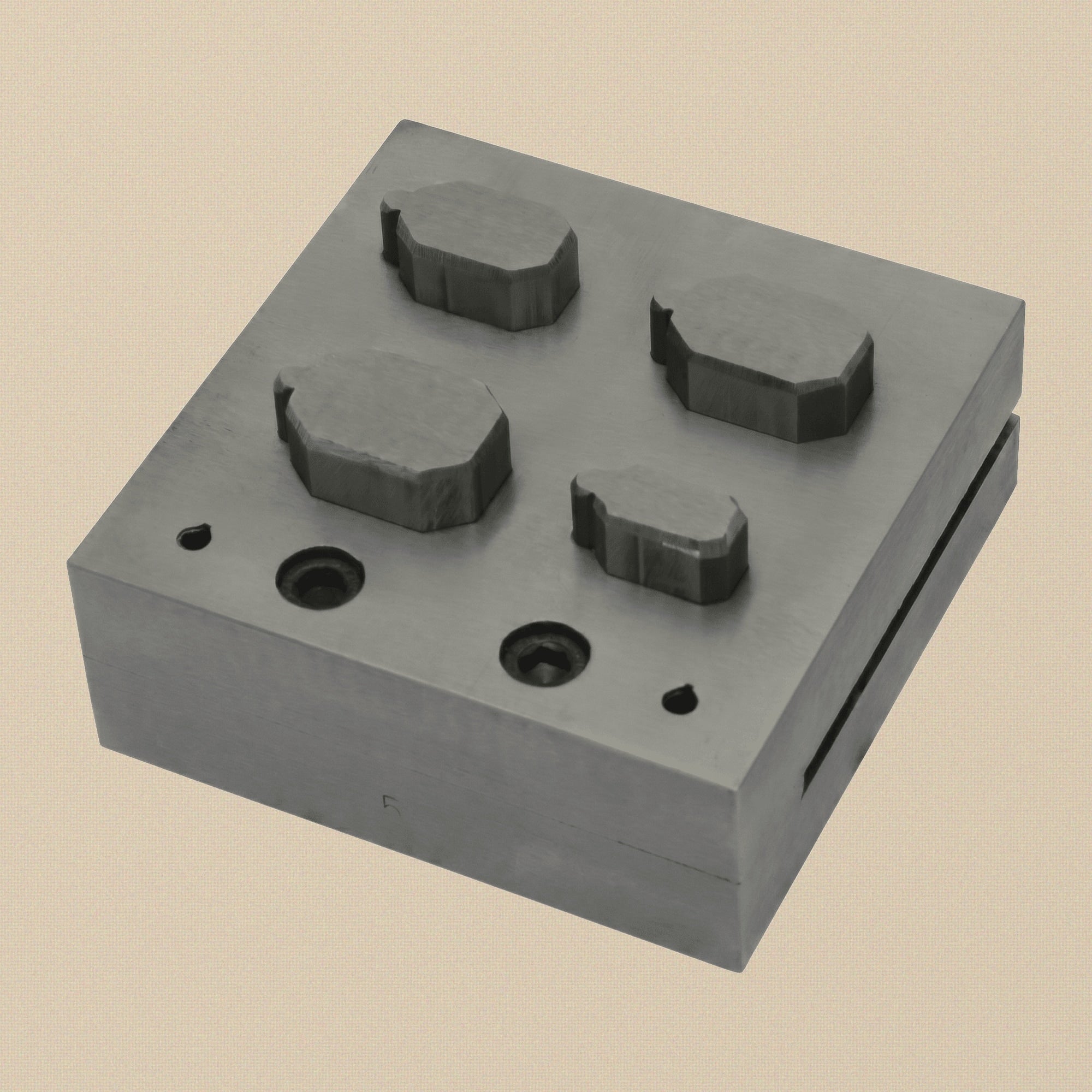 Close-up of the emerald-cut die slots on the 76mm square steel disc cutter block.
