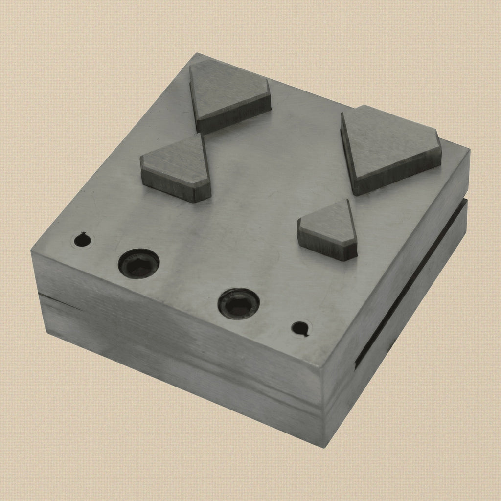 Close-up of the four diamond-shaped apertures in the steel die block.
