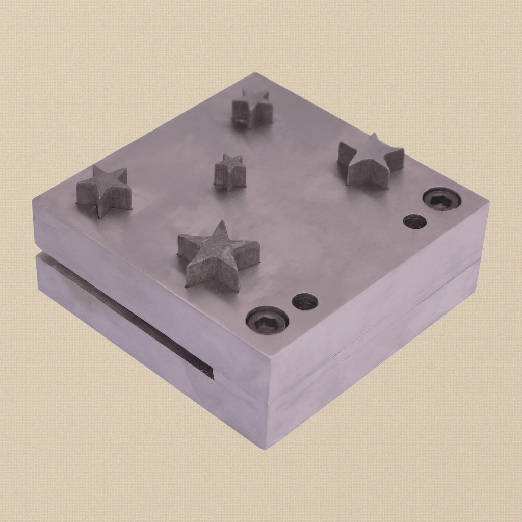 Close-up of the tempered high-carbon steel die block, showing the five star-shaped cutting holes.