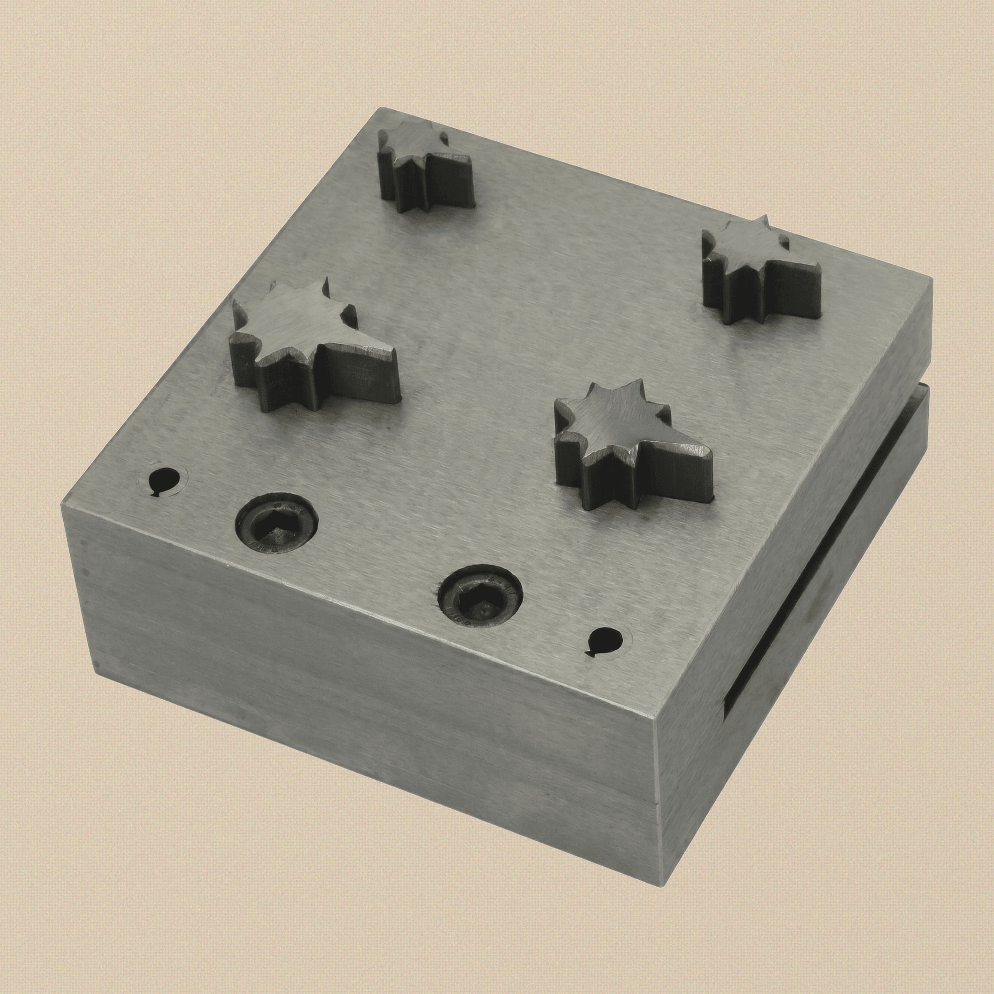 Close-up of the hardened steel 3-inch die block showing the four sparkle star shaped holes.