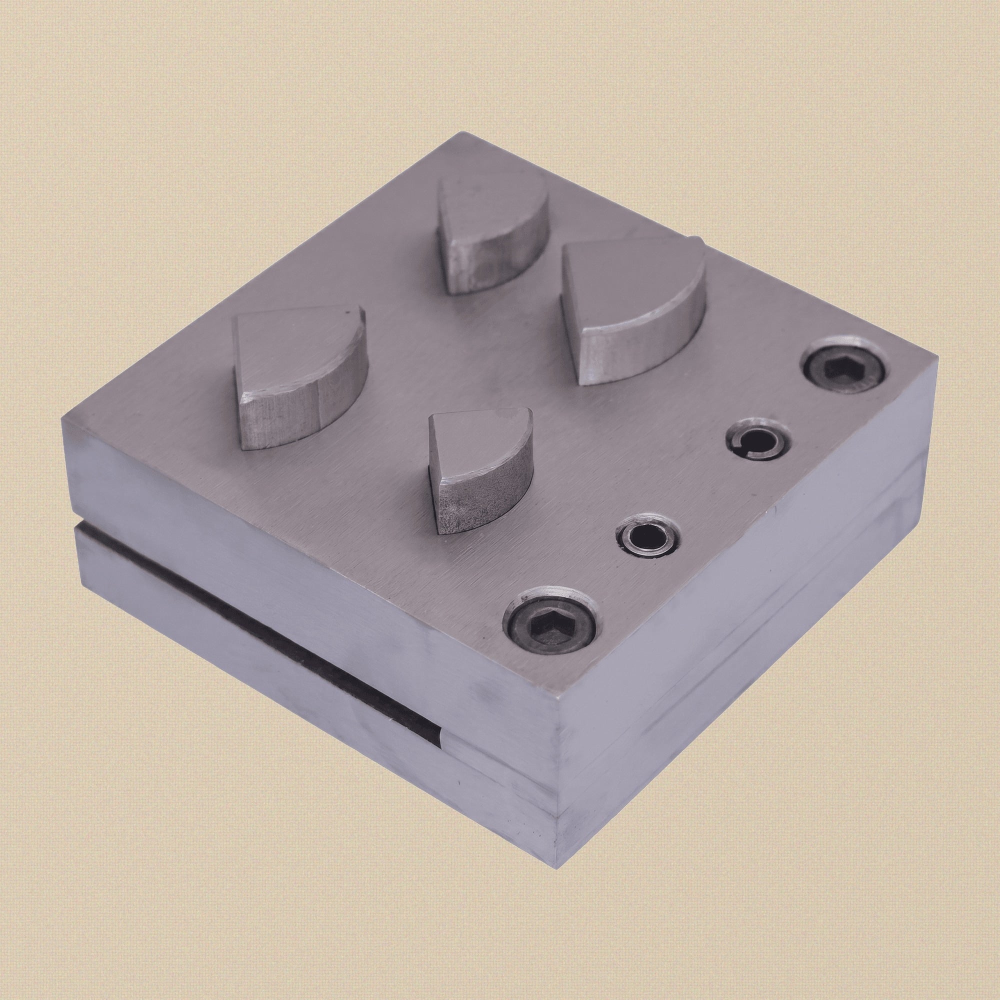 The 76mm square steel die block showing the four quarter circle cutting slots.