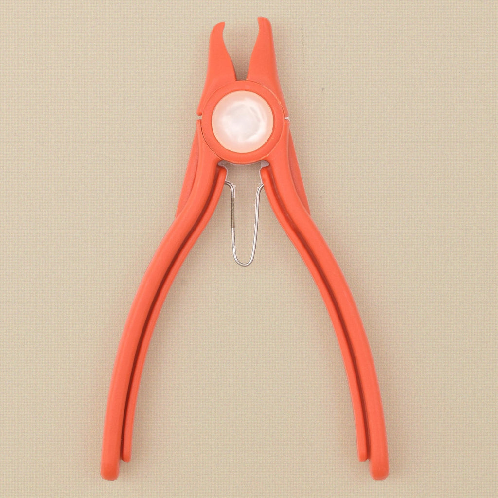 Orange plastic stone setting pliers standing, jaws upward