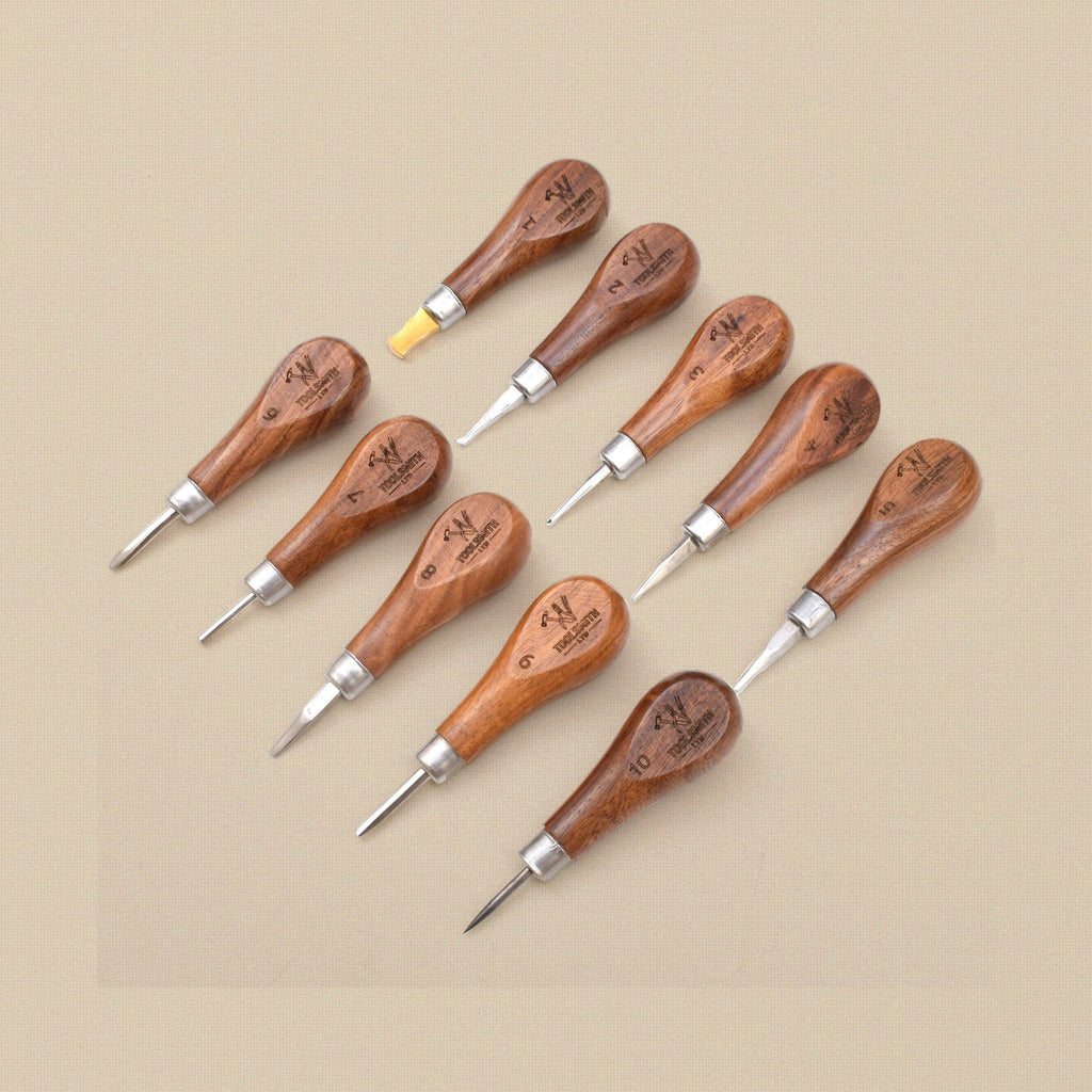 Ten stone setting tools with wooden handles laid out in two rows