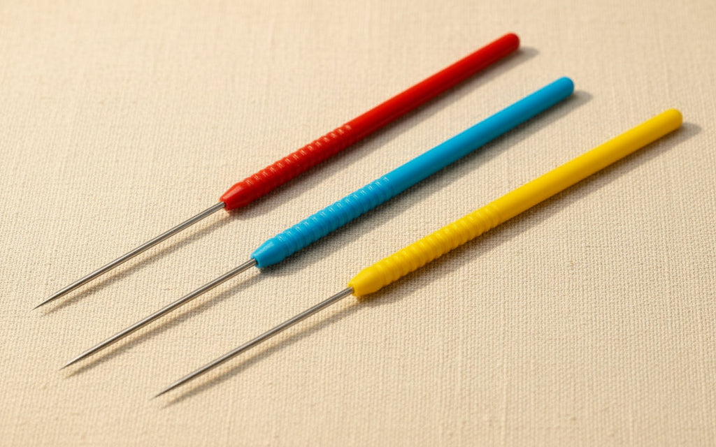 Close-up of three titanium soldering picks with coloured handles, showing their non-stick tips.