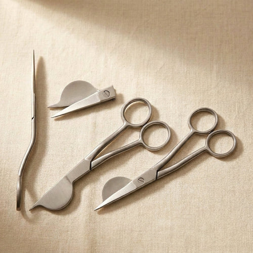 Curved half-duckbill appliqué scissors with offset handle for precise fabric cutting.