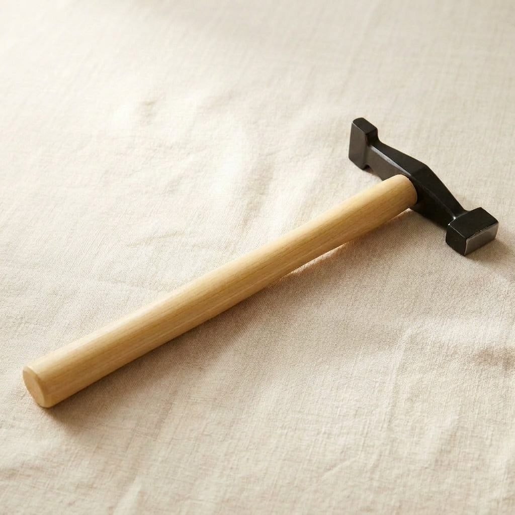 Silversmith grooving hammer with 90-degree head and wooden handle for detailed metalwork.