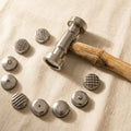 Professional metalworking texturing hammer with nine patterned interchangeable faces and wooden handle.