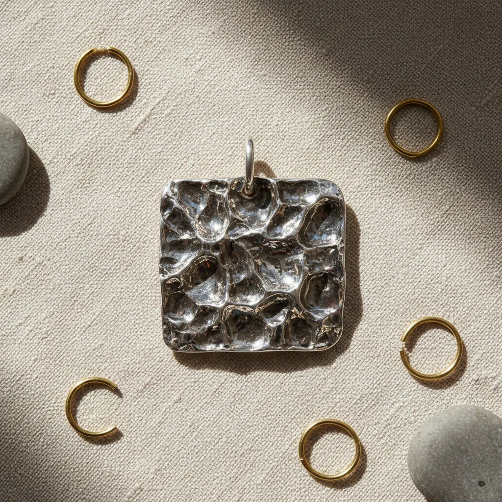 The wrinkled, molten-like surface of a reticulated silver pendant after heating.